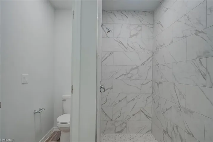 Full bathroom featuring toilet and a shower stall