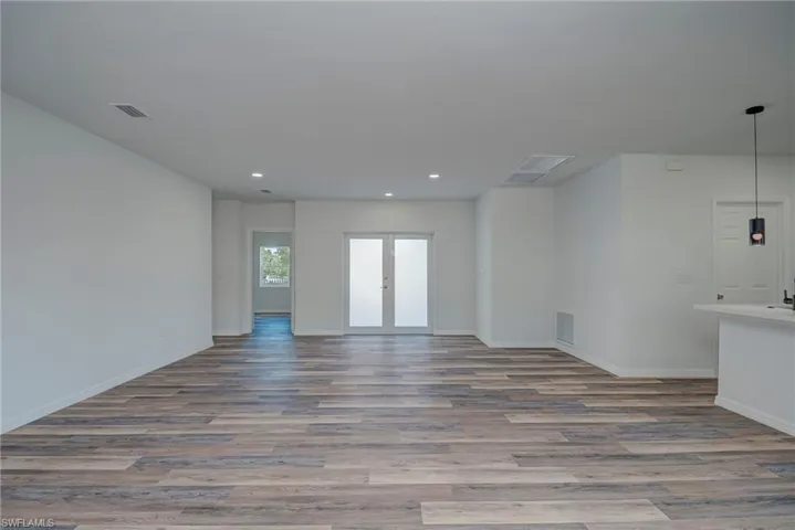 Unfurnished living room featuring wood finished floors, recessed lighting, and french doors