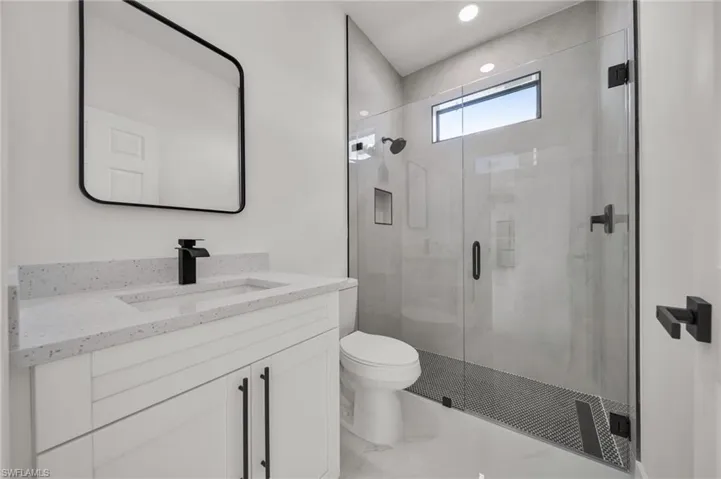 Bathroom featuring a marble finish shower, vanity, and recessed lighting