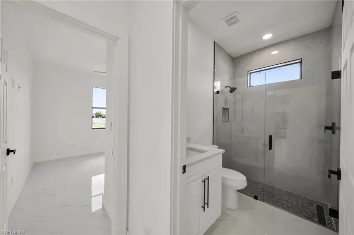 Full bathroom with vanity, a stall shower, light marble finish floors, and recessed lighting