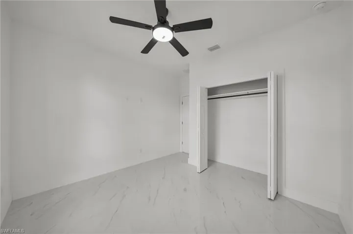 Unfurnished bedroom with light marble finish floors, a ceiling fan, and a closet
