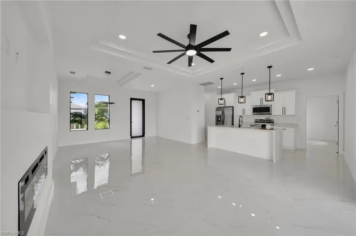 Unfurnished living room featuring light marble finish floors, a raised ceiling, recessed lighting, and ceiling fan