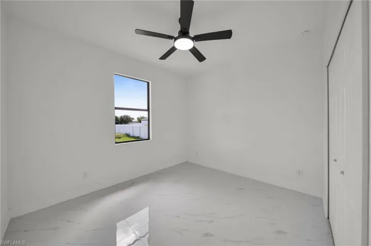 Empty room featuring light marble finish floors and a ceiling fan
