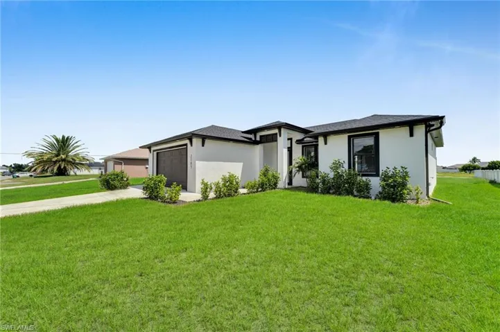 Prairie-style house featuring stucco siding, driveway, a garage, and a front lawn