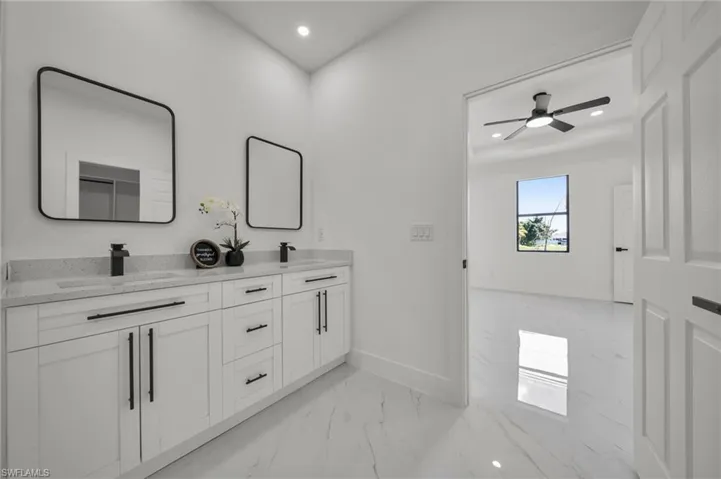 Full bath with double vanity, light marble finish flooring, recessed lighting, and a ceiling fan