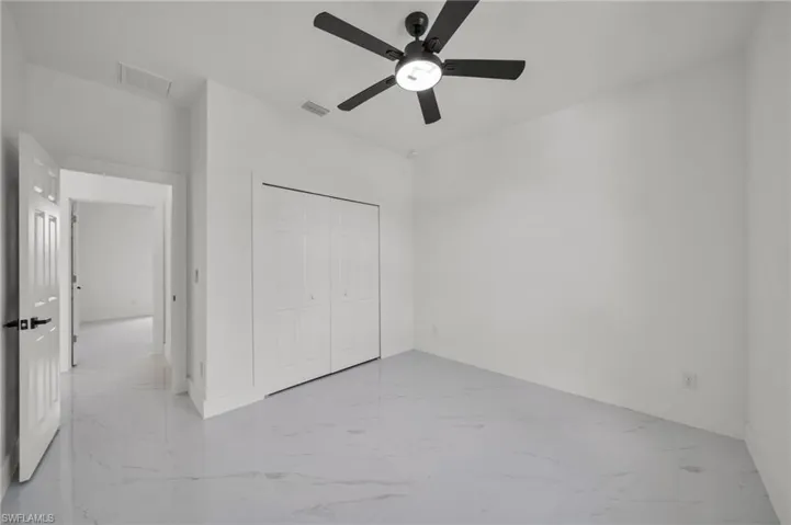 Unfurnished bedroom with light marble finish flooring, a closet, and a ceiling fan