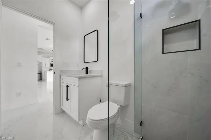 Full bath with vanity, light marble finish flooring, and a shower with shower door