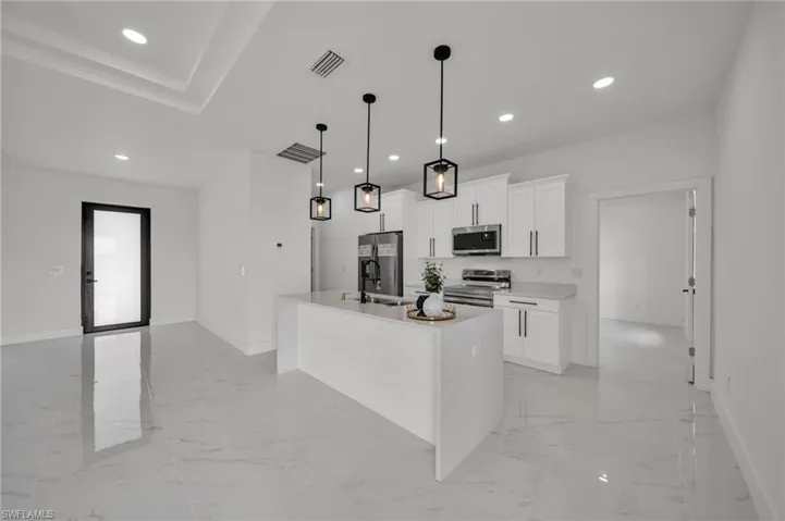 Kitchen with pendant lighting, white cabinetry, an island with sink, recessed lighting, and appliances with stainless steel finishes