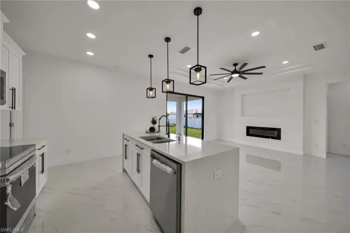 Kitchen featuring white cabinets, light marble finish floors, a glass covered fireplace, and recessed lighting