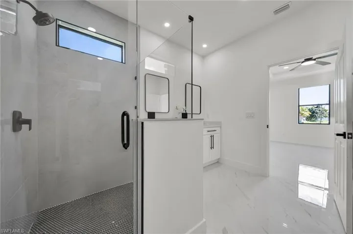 Bathroom featuring a marble finish shower, vanity, recessed lighting, and light marble finish flooring