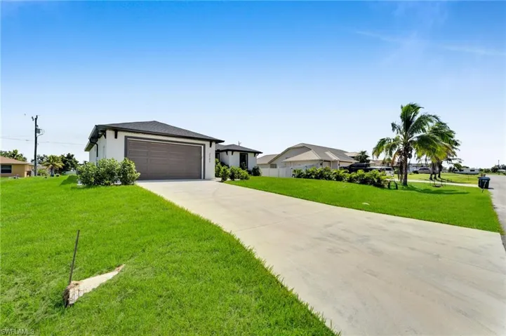 View of front of home with a front lawn, driveway, stucco siding, and an attached garage