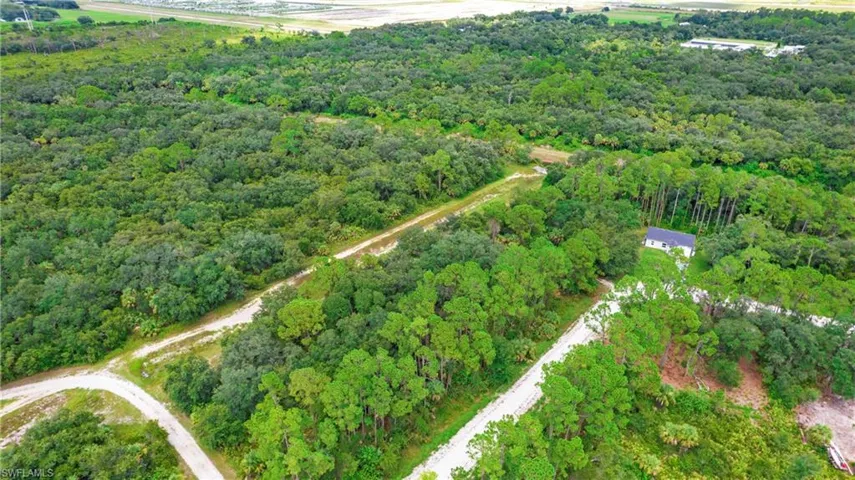 Aerial view of property and surrounding area with a heavily wooded area