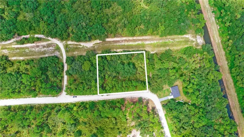 Aerial view of property's location with a heavily wooded area and property parcel outlined