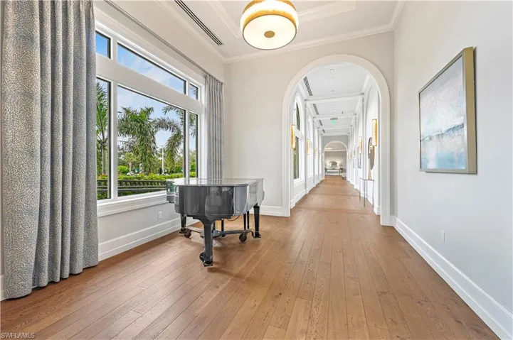 Hall featuring arched walkways, hardwood / wood-style floors, and ornamental molding