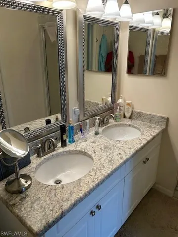 Full bath featuring baseboards, double vanity, and a sink
