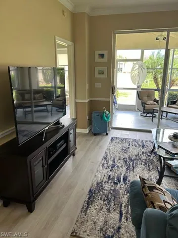 Living room with baseboards, light wood-style floors, and ornamental molding