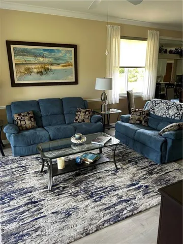 Living area with ornamental molding and wood finished floors