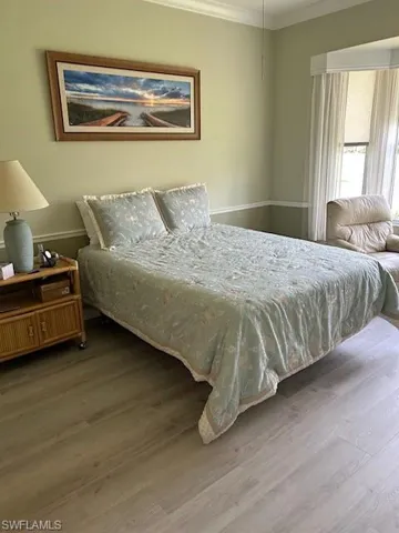 Bedroom with ornamental molding and wood finished floors