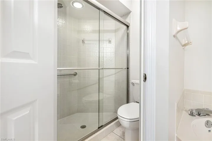 Walk-in shower with clear glass enclosure, integrated seating, and a recessed light fixture