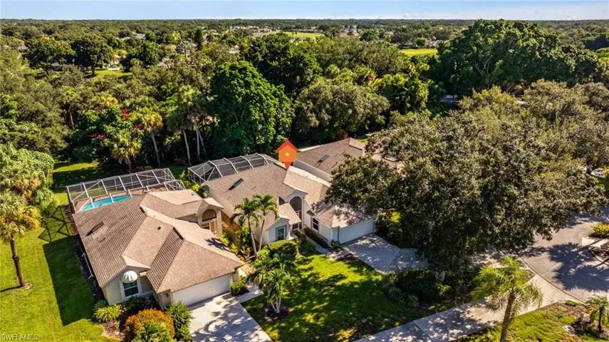 Tile roof residence with a screened pool enclosure, mature landscaping, and an attached garage