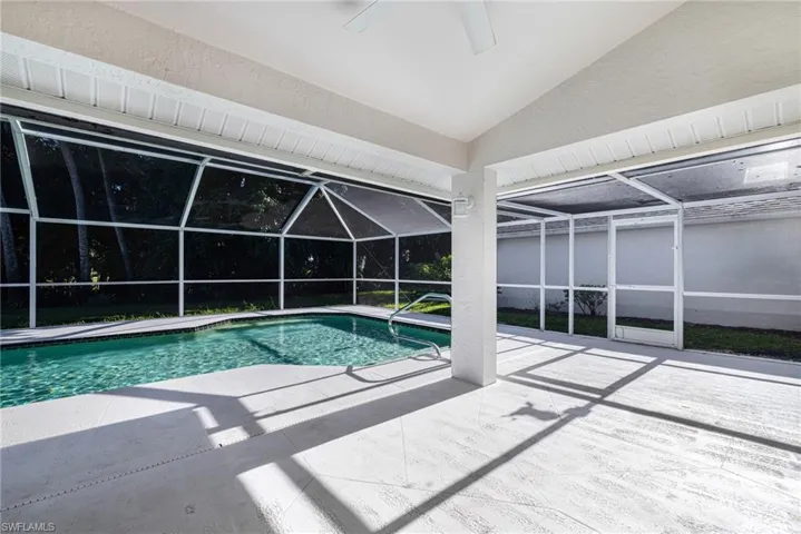 Screened-in pool deck with a rectangular swimming pool, integrated steps, and a handrail