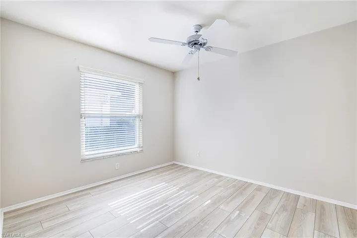 Light wood-finish flooring, white walls, and a ceiling fan with light fixture