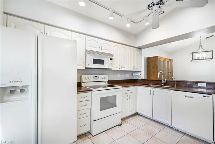 Kitchen featuring white cabinetry, brown countertops, white appliances, and tiled flooring