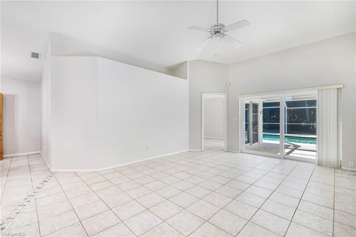 Vaulted ceilings, a ceiling fan, and white tile flooring with decorative inlay