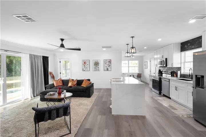 Living room featuring sink, ornamental molding, hardwood / wood-style flooring, and ceiling fan with notable chandelier
