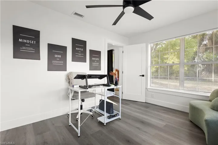 Office with dark wood-type flooring and ceiling fan