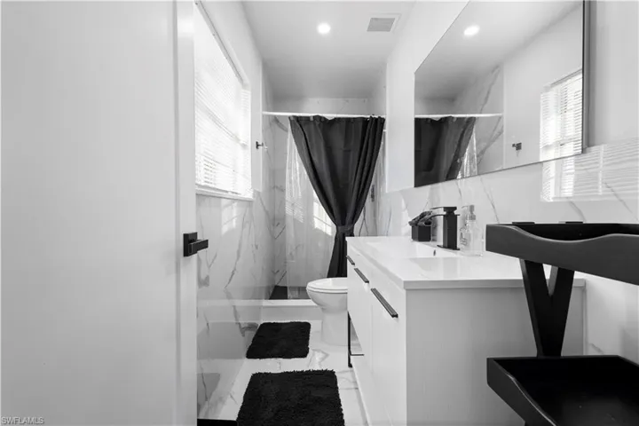 Bathroom with tile flooring, walk in shower, vanity, and toilet