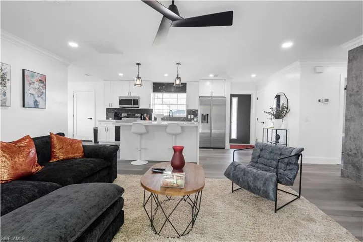 Living room featuring ornamental molding, light wood-type flooring, and ceiling fan