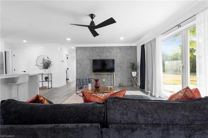 Living room featuring wood-type flooring, ornamental molding, and ceiling fan