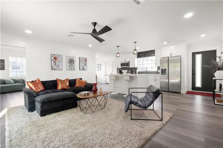 Living room with wood-type flooring, ornamental molding, and ceiling fan