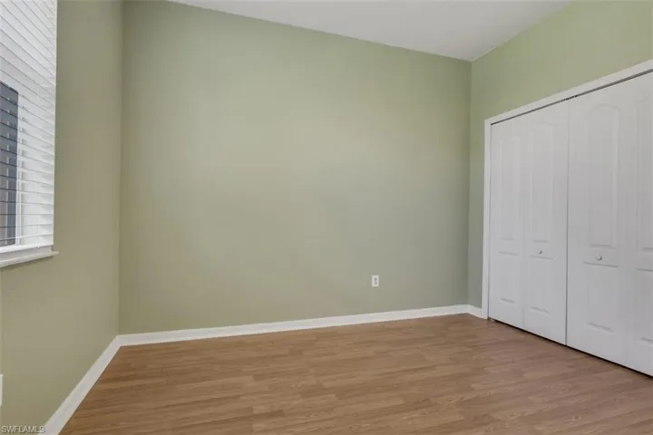 Unfurnished bedroom with wood finished floors and a closet