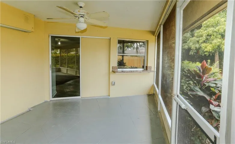 Screened patio featuring a ceiling fan, sliding glass door, fixed window, and a granite-finish countertop
