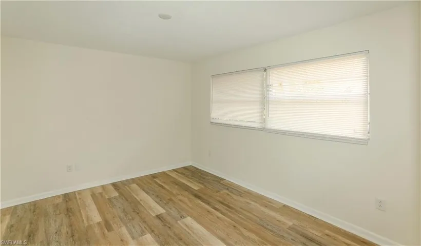Room with wood-finish flooring, light-toned walls, and white baseboards