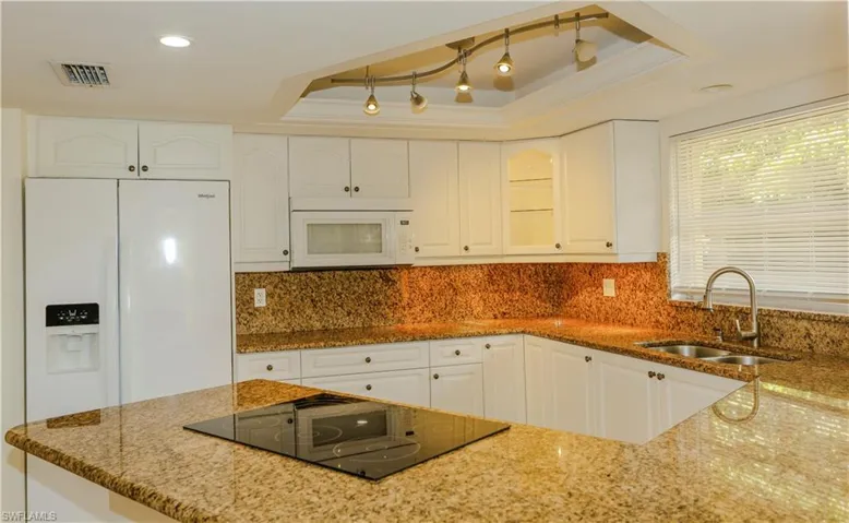 Kitchen featuring white cabinetry, solid surface countertops, and a built-in cooktop