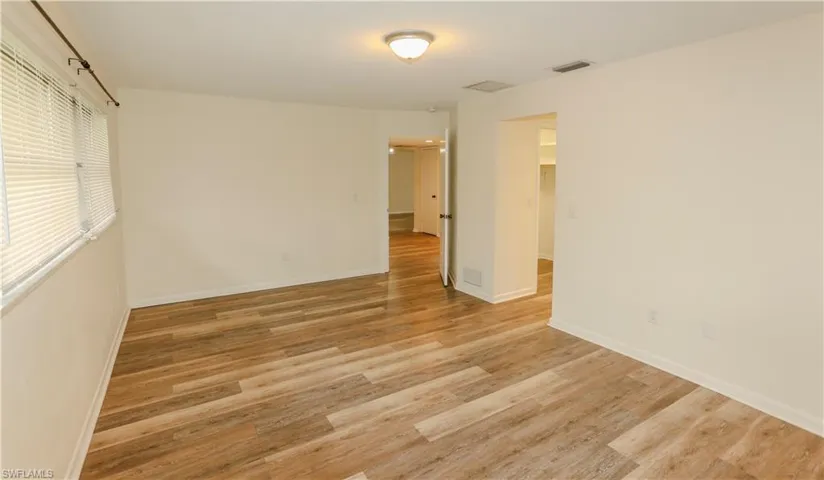 Spacious room featuring wood-finish flooring, light-toned walls, and white trim