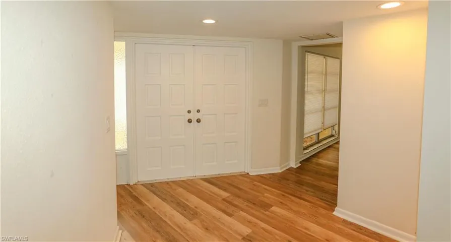 Entryway featuring double panel doors with brass hardware, wood-finish flooring, recessed lighting, and white baseboards