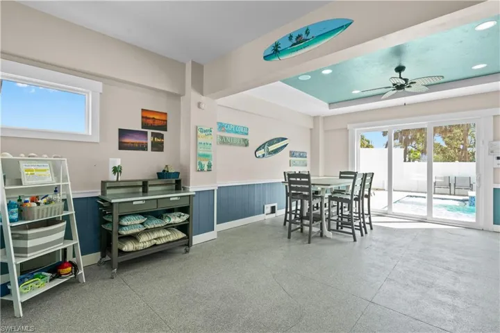Spacious indoor-outdoor living area featuring durable flooring, a vaulted ceiling with recessed lighting and a ceiling fan, and large sliding glass doors opening to a private pool area