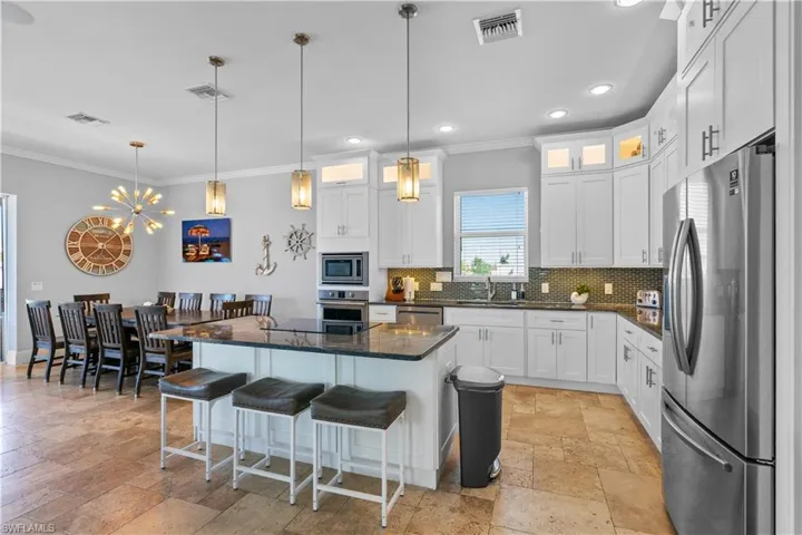 Spacious kitchen featuring white cabinetry, granite countertops, stainless steel appliances, a tiled backsplash, and recessed lighting