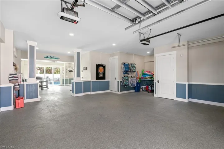Spacious garage featuring a finished gray floor and blue wainscoting