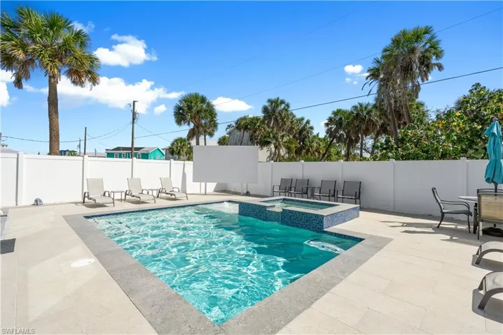 Outdoor entertainment area featuring an in-ground swimming pool, an integrated spa with blue mosaic tiling, and extensive light-toned paver decking