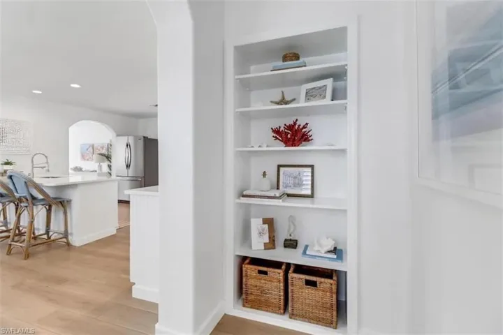 Corridor with built in shelves, light hardwood / wood-style flooring, and sink