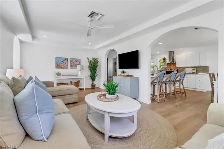 Living room with a tray ceiling, ceiling fan, sink, and light hardwood / wood-style floors