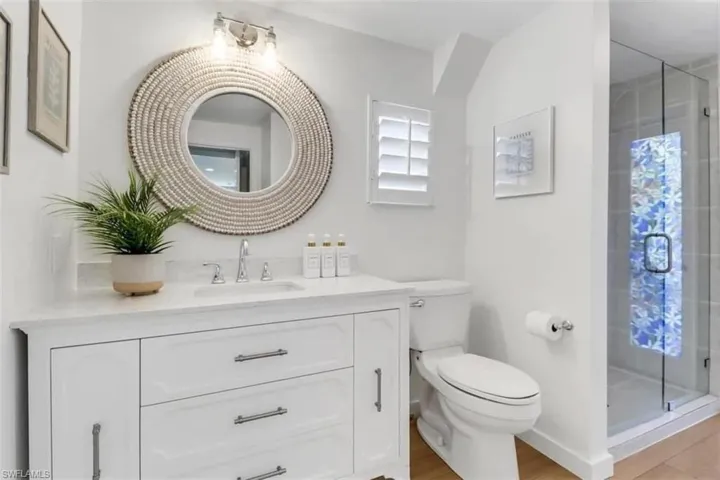 Bathroom featuring hardwood / wood-style flooring, vanity, toilet, and a shower with door