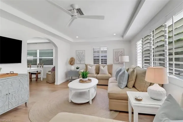 Living room featuring a tray ceiling, a healthy amount of sunlight, ceiling fan, and light hardwood / wood-style floors