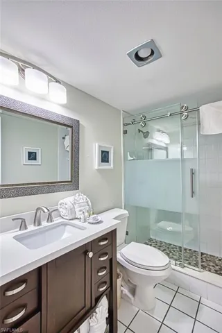 Full bathroom with light tile patterned floors, a textured ceiling, a stall shower, and vanity