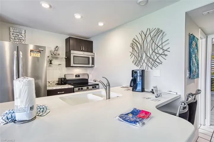 Kitchen featuring stainless steel appliances, dark brown cabinetry, a peninsula, recessed lighting, and tile patterned flooring
